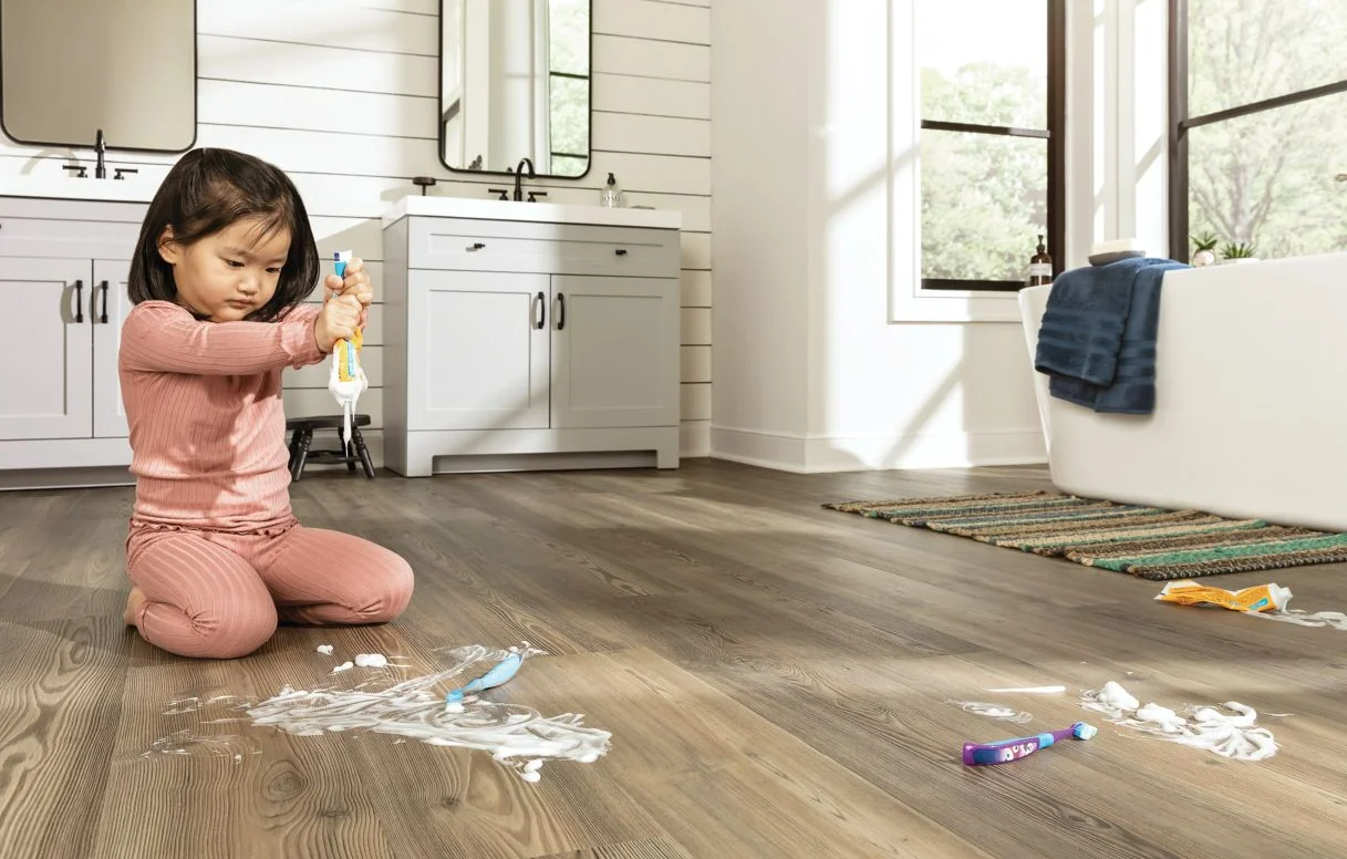A child squeezes a tube of toothpaste on a Mohawk spillproof lvt bathroom floor.
